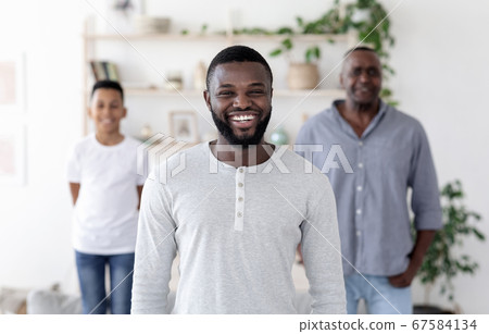 Male Generations. Happy Black Man On Foreground Posing With His Son And Dad At Home 67584134