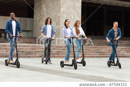 Five friends having pleasant ride on motorized kick scooters 67584153