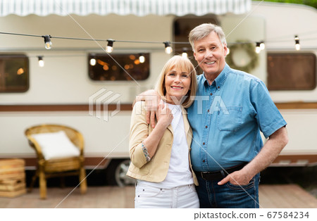 Portrait of mature couple embracing near their motorhome at campground, copy space 67584234