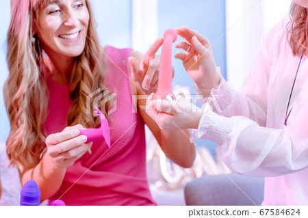 Woman asking saleslady for details of dildo on adult toy party 67584624