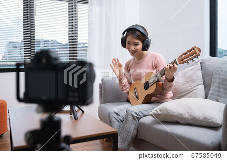 Asian woman blogger recording and live steam playing guitar on social media 67585049