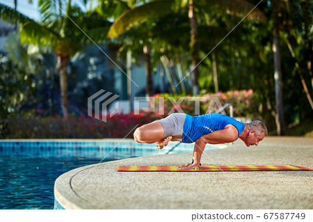 A man practice yoga near to swimming pool A man practice yoga near to swimming pool 67587749