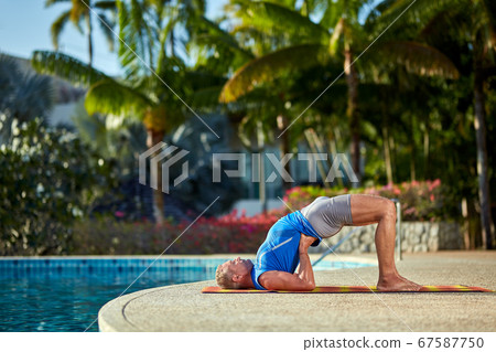A man practice yoga near to swimming pool A man practice yoga near to swimming pool 67587750