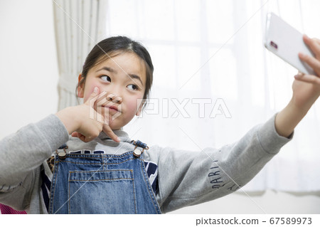 小學女孩在自修室採取與智能手機的自拍照 67589973