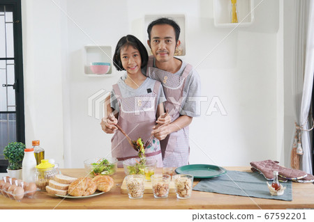 Father and daughter cooks in the kitchen at home, 67592201