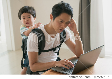 Image of father working at home while caring for his child 67592396