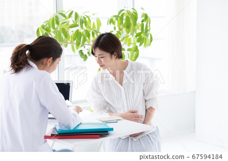 A woman and a doctor undergoing a pregnancy checkup 67594184