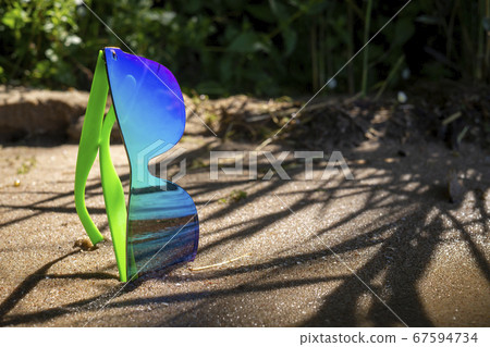 Pair of trendy modern sunglasses on coastal sand Pair of trendy modern sunglasses on coastal sand 67594734