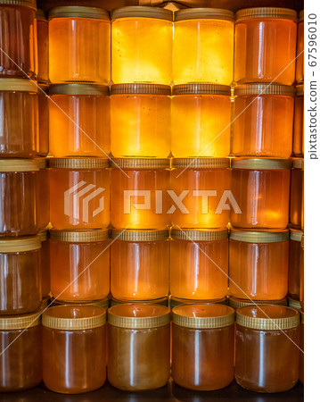 Tower and rows of Golden yellow honey in glass jar on wooden board Closeup Copy space 67596010