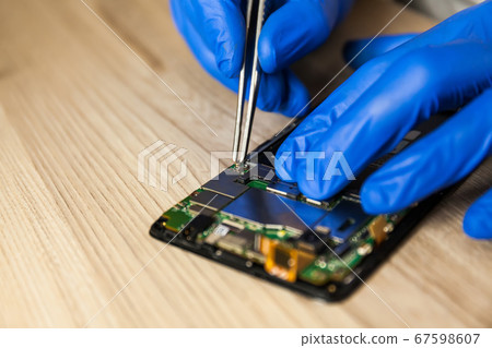 Technician repairing mobile phone at table, 67598607