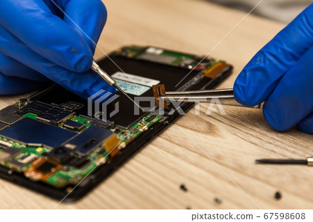Technician repairing mobile phone at table, 67598608