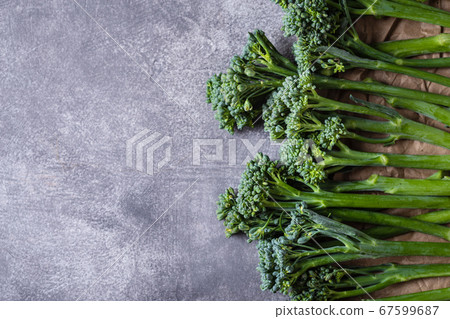 Border of broccolini on grey stone background. Border of broccolini on grey stone background. 67599687