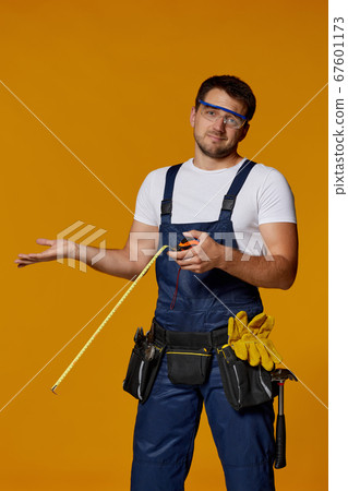 repairman worker in uniform holding measure tape. 67601173
