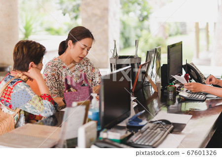 Two female guest checking hotel documents at reception. Two female guest checking hotel documents at reception. 67601326