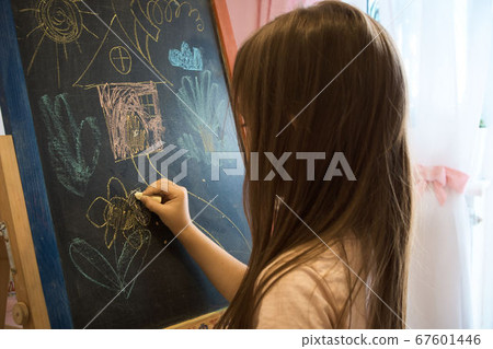 Little girl draws with chalk on the blackboard . 67601446