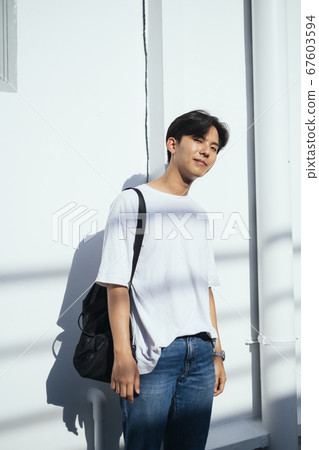 Guy in sunlight at white wall. Guy in sunlight at white wall. 67603594