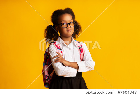 Serious Black School Girl Crossing Hands Posing Over Yellow Background 67604348