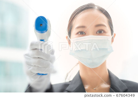 一個女人用非接觸式溫度計測溫 一個女人用非接觸式溫度計測溫 67604349