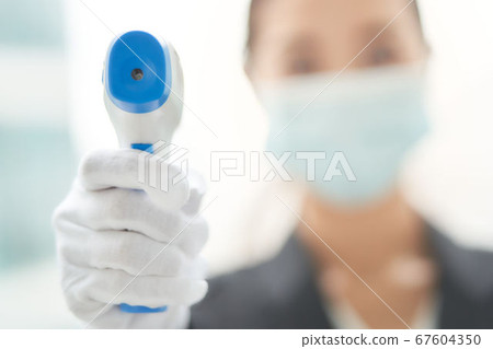 一個女人用非接觸式溫度計進行溫度測量 67604350