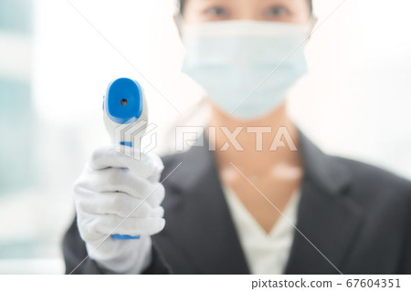一個女人用非接觸式溫度計進行溫度測量 一個女人用非接觸式溫度計進行溫度測量 67604351