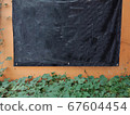 Empty Hanging black banner on wall and green leaf 67604454