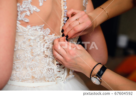 bridesmaid hands fastens buttons on the back of the bride bridesmaid hands fastens buttons on the back of the bride 67604592
