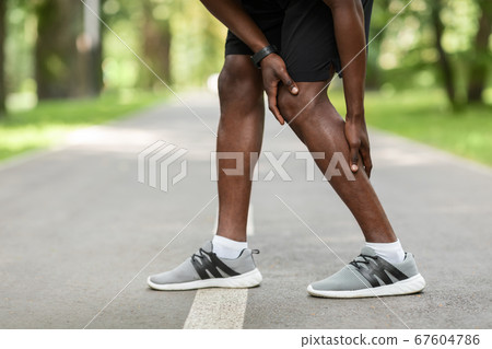 African guy rubbing his aching leg, got cramp while jogging 67604786