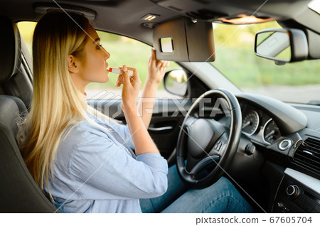 Female student applies makeup, driving school 67605704