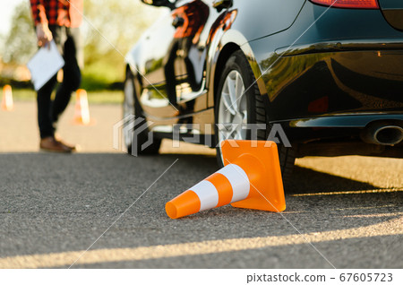 Male instructor at the car, downed traffic cone Male instructor at the car, downed traffic cone 67605723