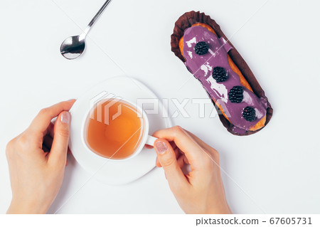Female hands hold cup of tea next to cake 67605731