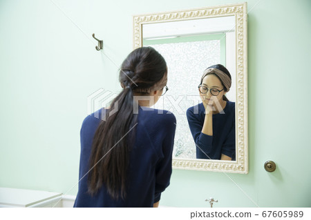 Woman looking in the mirror 67605989