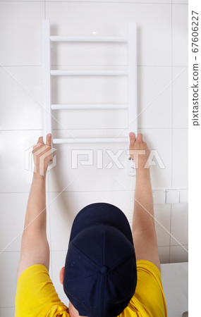 Renovation in the bathroom. A plumber installs a heated towel rail.  67606227
