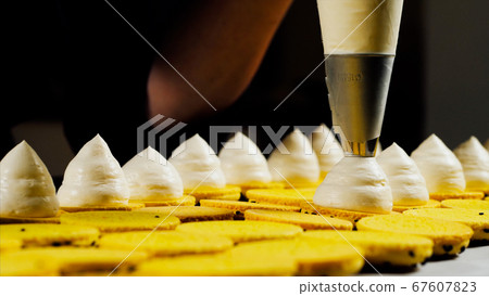 Chef is making a batch of macarons, close-up. 67607823