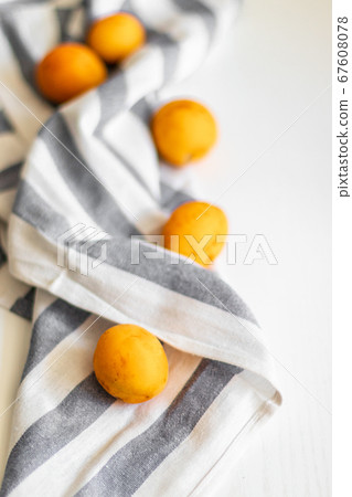 Ripe fresh apricots with striped towel on a white background, top view, space for text. 67608078