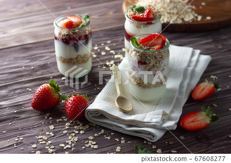 Natural yogurt in little jar with jam, muesli and fresh strawberry, mint leaves. Healthy breakfast concept. Natural yogurt in little jar with jam, muesli and fresh strawberry, mint leaves. Healthy breakfast concept. 67608277