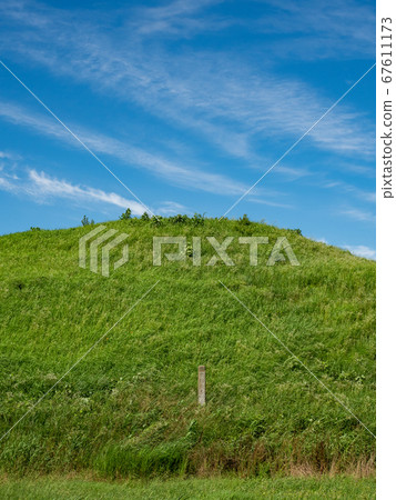 Under the blue sky with clouds in the lush burial mounds in early summer Under the blue sky with clouds in the lush burial mounds in early summer 67611173