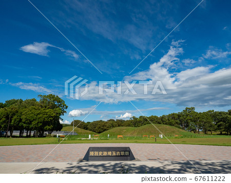 Under the blue sky with clouds in the lush burial mounds in early summer 67611222