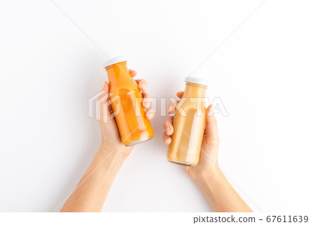 Overhead shot of woman hands holding bottles of fruit and vegetable juices Overhead shot of woman hands holding bottles of fruit and vegetable juices 67611639