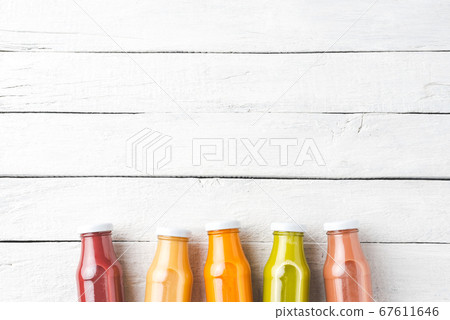 Fresh fruit and vegetable juices in bottles on white wooden background with copyspace 67611646