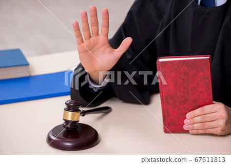 Young male judge working in courthouse 67611813