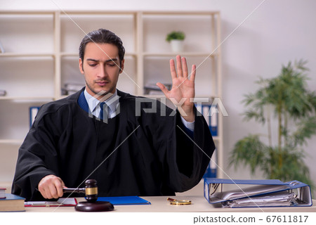 Young male judge working in courthouse 67611817