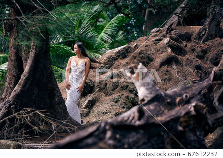 Beautiful asian woman posing in a long white dress Beautiful asian woman posing in a long white dress 67612232