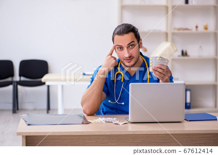 Young male doctor working in the clinic Young male doctor working in the clinic 67612414