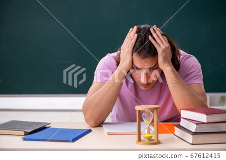 Young male student in the classroom at time management concept Young male student in the classroom at time management concept 67612415