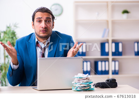 Young male employee unhappy with excessive work 67613018