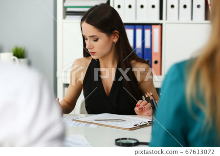 Beautiful female clerk working with financial papers Beautiful female clerk working with financial papers 67613072