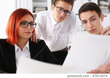 Three young managers discussing documents in office Three young managers discussing documents in office 67613074