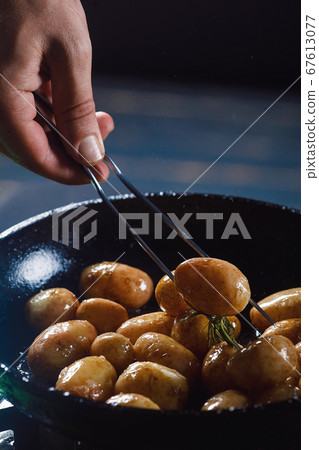 Boiled young potatoes with oil and roasted garlic, in a wooden dish. 67613077
