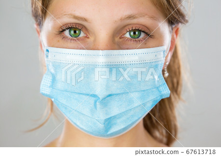 Close-up of a alert young blonde woman with face mask looking into camera Close-up of a alert young blonde woman with face mask looking into camera 67613718