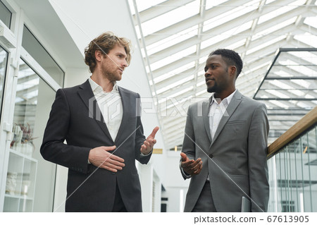 Two Modern Businessmen Walking in Office Building Two Modern Businessmen Walking in Office Building 67613905